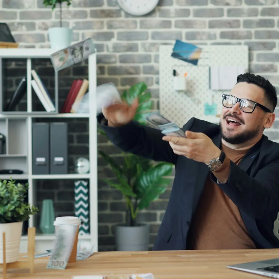 a man sitting at a desk holding a remote control