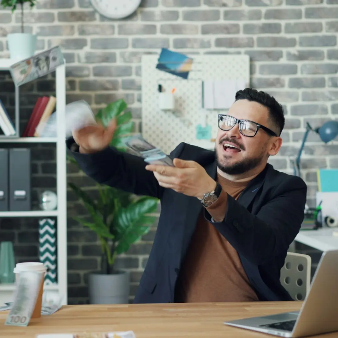 a man sitting at a desk holding a remote control